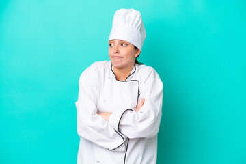 Young caucasian chef woman isolated on blue background making doubts gesture while lifting the shoulders