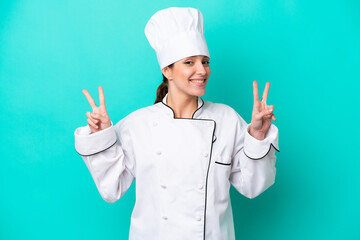 Young caucasian chef woman isolated on blue background showing victory sign with both hands