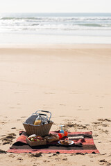 Picnic basket on beach. Basket, food and drinks on blanket on seashore. Picnic, food, relaxation concept