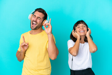 Young couple isolated on blue background listening music and singing
