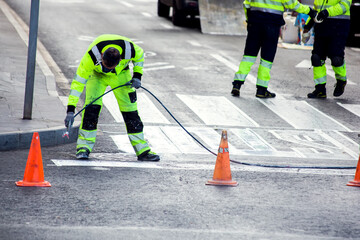 Obraz premium Traffic line painting. Workers painting white street lines on pedestrian crossing