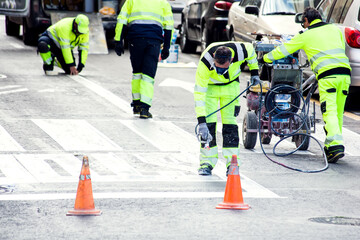 Obraz premium Traffic line painting. Workers painting white street lines on pedestrian crossing