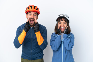 Young cyclist couple isolated on white background shouting and announcing something
