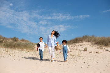 Mother and children walking on beach on sunny day. African American family spending time together on open air. Leisure, family time, parenting concept