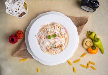 Creamy white dipped pasta in a plate top view on wooden background
