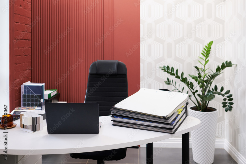 Poster workplace of designer with laptop and stack of folders on table at modern office