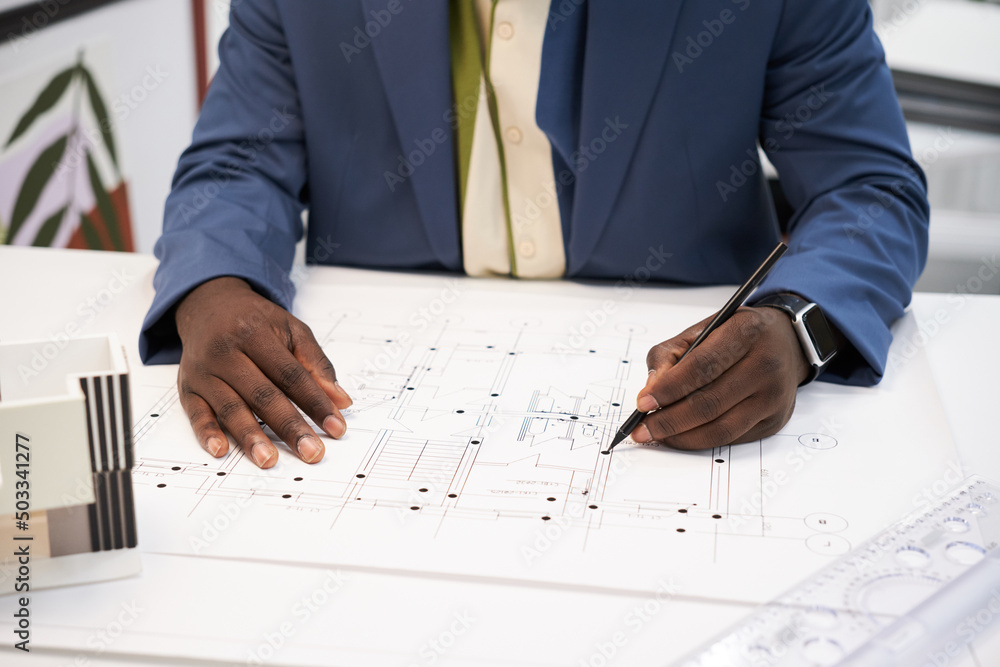 Poster close-up of african architect using pencil and ruler to draw project of construction plan at desk