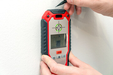 Man using stud finder to locate framing studs located behind the walling surface. Using a wall...