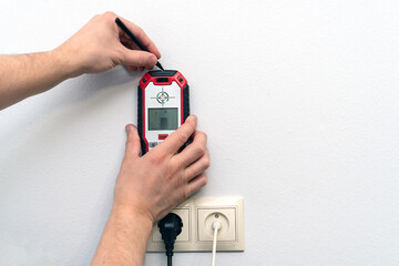 Man using a wall scanner to identify hidden electrical wiring. Space for text