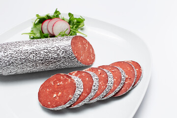 Close-up of cutted smoked vegan sausage on the plate, on white background.
