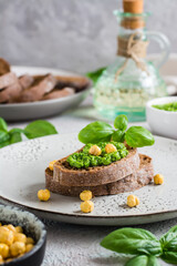 Fototapeta na wymiar Appetizing bruschetta made from rye bread, pesto and chickpeas on a plate. Vertical view