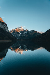Bergsee mit Spiegelung und verschneitem Berggipfel