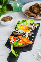 Appetizing sandwiches on rye bread with feta cheese, olives and vegetables. Vertical view