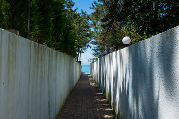 Narrow street leading to the sea. A path between two white walls.