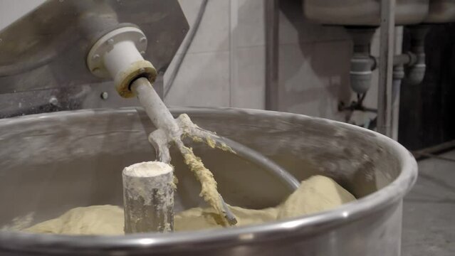 Industrial mixer for kneading dough. Mixing machinery at bakery. Dough preparing, kneading process in factory. Close view kneading machine preparing dough.