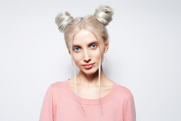 Studio portrait of beauty girl with blonde hair buns in pink shirt, on white.