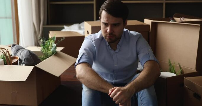 Bank debtor, sad man leave house sit on floor with packed belongings in big cardboard boxes feels depressed having financial problem. Eviction, bankruptcy or debt, long relocation day, divorce concept