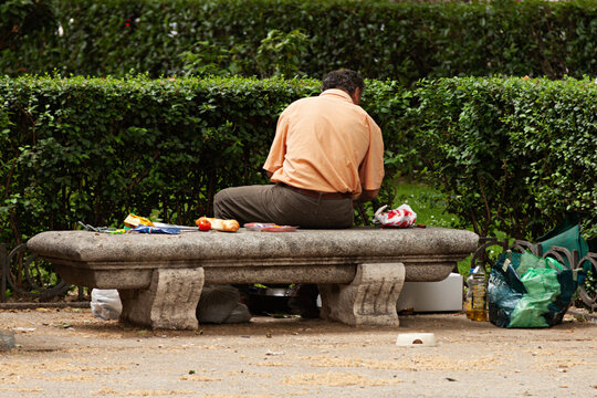 Mendigo sentado en un banco con la comida y dem&aacute;s enseres.