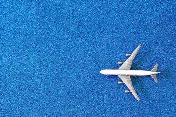 Toy airliner on a silvery light blue background. Concept of a romantic holiday flight. Concept of Christmas and New Year travel and relocation. Copy space