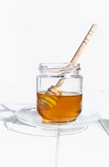 Glass jar with raw flower honey and wooden honey taster stick