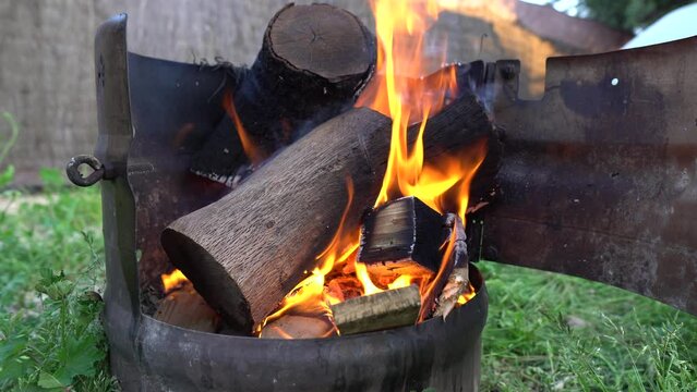 Llamas quemando troncos para hacer brasas en una barbacoa redonda casera