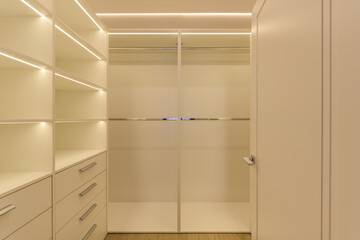 Spacious, empty, modern backlit wardrobe in light colours