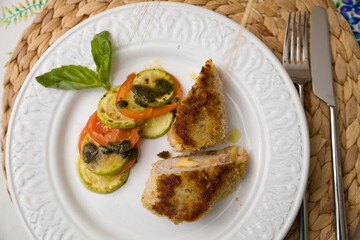 Juicy fresh cutlet cut into pieces with fresh fried tomatoes and zucchini.