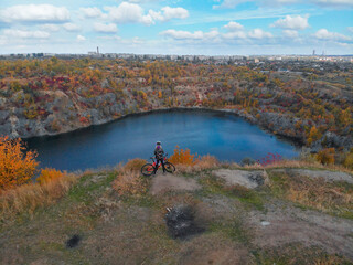 Young woman cycling on bike outdoors aerial view from above. Aerial view of happy sport girl relaxing near beautiful mountains lake from above, sport and fitness concept