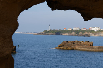 The view of the Biarritz lighthouse seen through rock arch . France. - 503348444