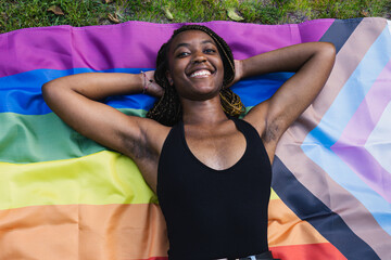 Black girl lying on LGTBQ flag rests after pride day.