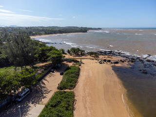 Beautiful beach with dark sands and black rocks like a volcano. Manguinhos, Espirito Santo, Brazil - aerial drone view