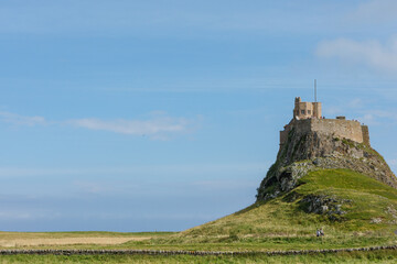 Lindisfarne/England: 10th Sept 2019: Holy Island Castle view from coastline with tide in blue sky