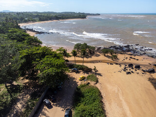 Beautiful beach with dark sands and black rocks like a volcano. Manguinhos, Espirito Santo, Brazil - aerial drone view