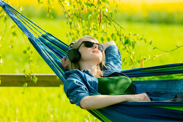 Young woman in headphones listen a music in hammock in countryside