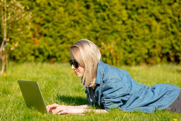 Woman with computer lying on grass in a garden