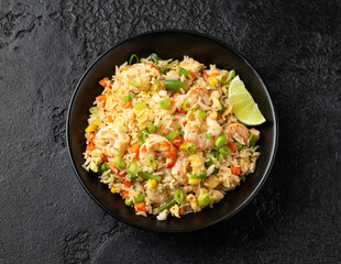 Prawn fried rice with eggs and vegetables in black bowl. Healthy asian food.