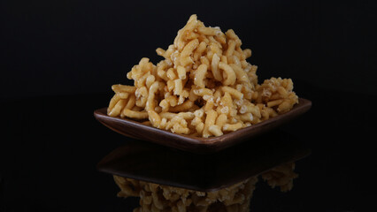 close-up of sweet national Russian Tatar dessert chak-chak from dough with honey on a black background with reflection in a wooden plate on the table