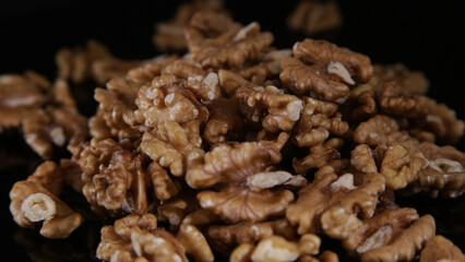 close-up of scattered walnuts on a mirrored black table in the dark