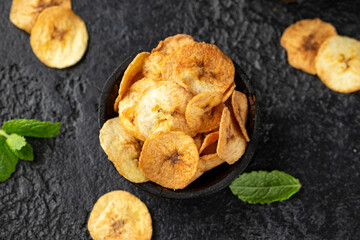 Dried banana chips, snack in rustic coconut bowl © grinchh
