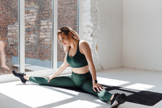 Healthy woman stretching legs after trainings on yoga mat