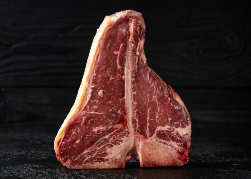 Raw T Bone beef steak with herb and seasoning on rustic background