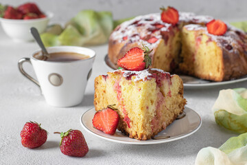 Charlotte pie strawberries with a cut piece and also cup of coffee on a gray table