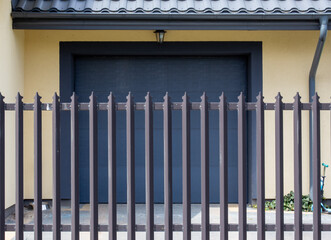 Closed garage door and entrance gate to the house. Safety of life in a detached house. Metal fence,...