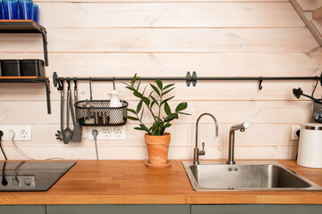 Kitchen brass utensils, chef accessories. Hanging kitchen with white tiles wall and wood tabletop.Kitchen background copy space 