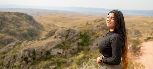 Portrait of Latin woman dressed in black with a cap having fun during the day of trekking in the...