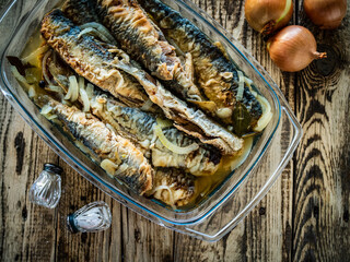 Fish dish - marinated fried herrings on wooden table
