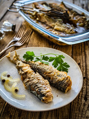 Fish dish - marinated fried herrings on wooden table
