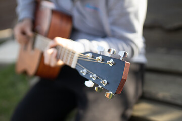 Young handsome man playing spanish guitar in green garden