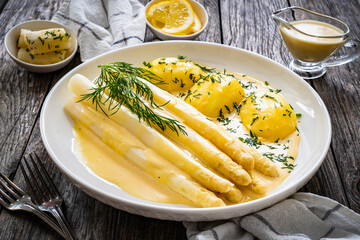 White boiled asparagus in hollandaise sauce with potato puree served on wooden black table
