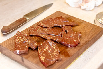 Raw liver on wooden board with spices and condiments on wooden table close-up